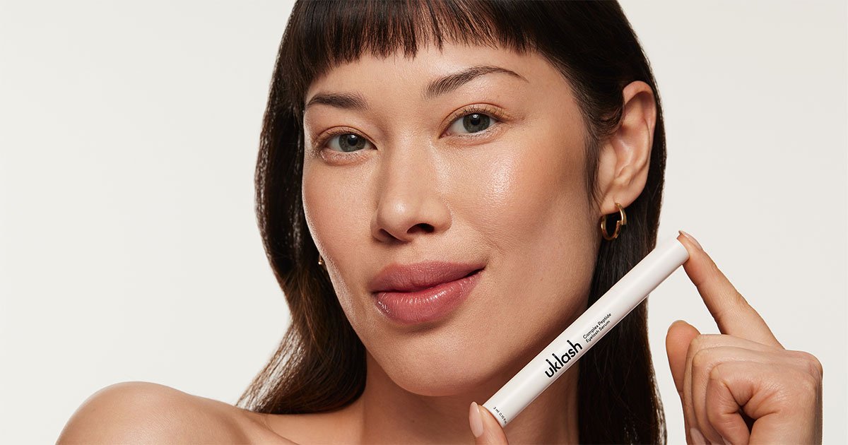A woman holding the UKLASH Complex Peptide Eyelash Serum